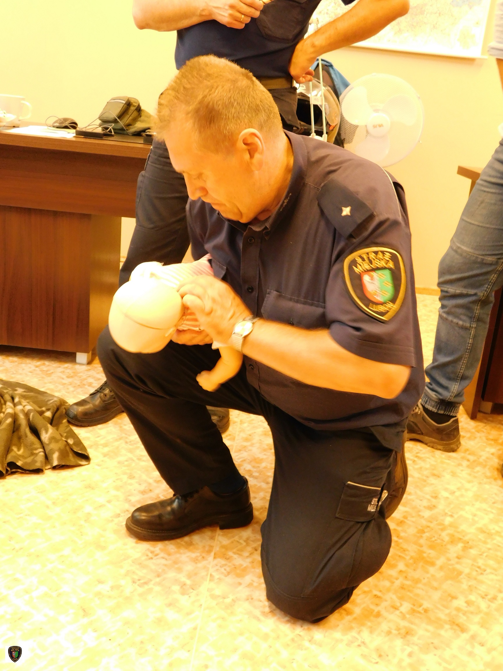 zdjęcie przedstawia strażnika miejskiego ćwiczącego na manekinie udzielanie pierwszej pomocy dziecku przy zadławieniu 