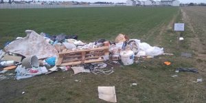 Zdjęcie przedstawia śmieci wyrzucone na pole