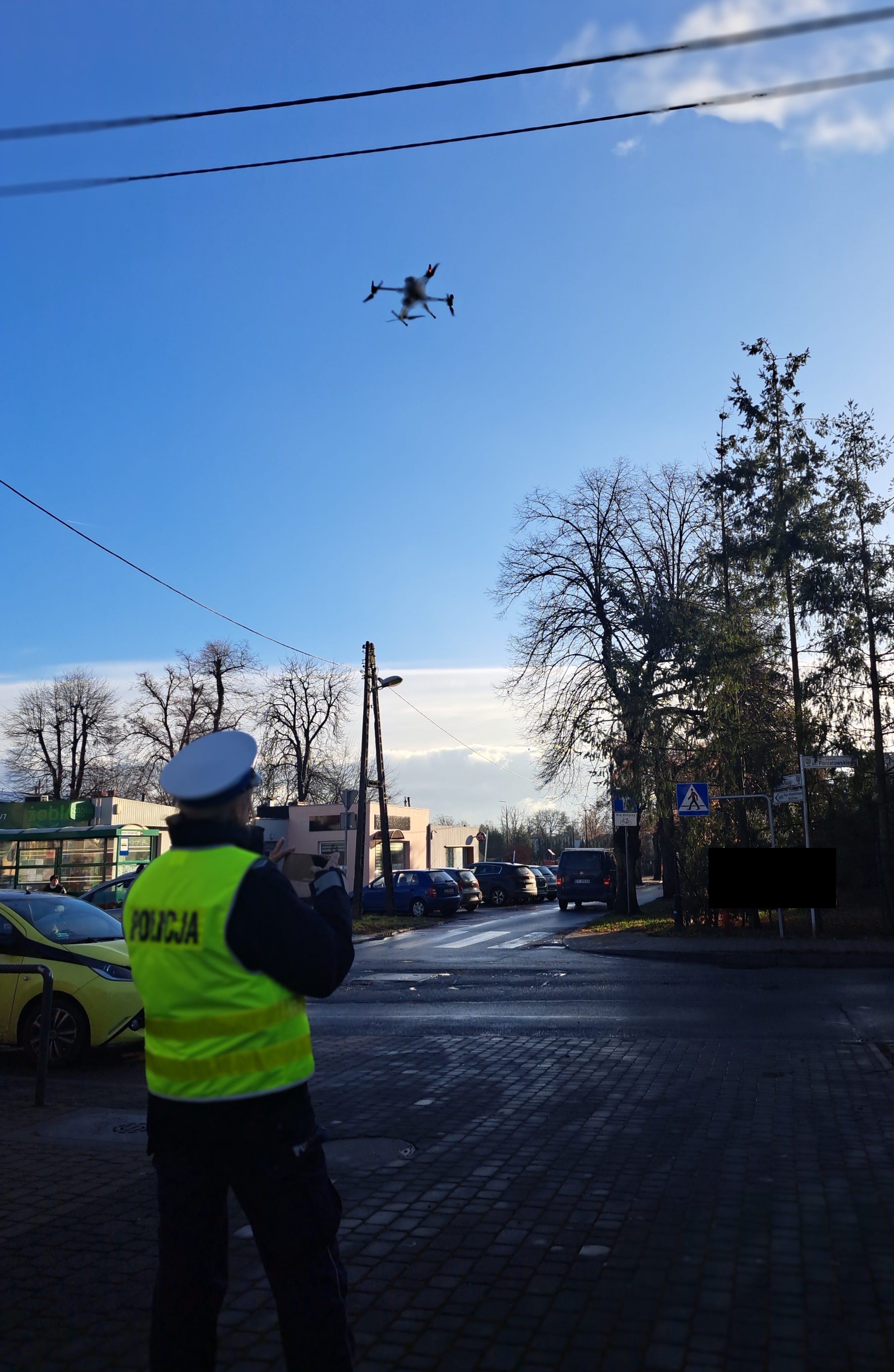 Zdjęcie przedstawia policjanta obsługującego drona