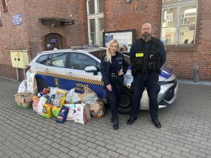 Zdjęcie przedstawia strażników miejskich oraz radiowóz z darami zebranymi dla Wielkopolskiego Inspektoratu Ochrony Zwierząt