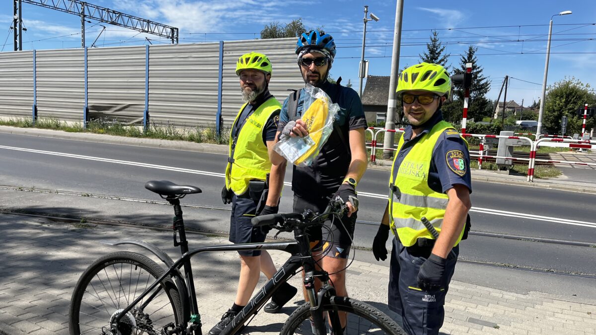 Zdjęcie przedstawia strażników miejskich i rowerzystę podczas akcji "Bądź bezpieczny na drodze"